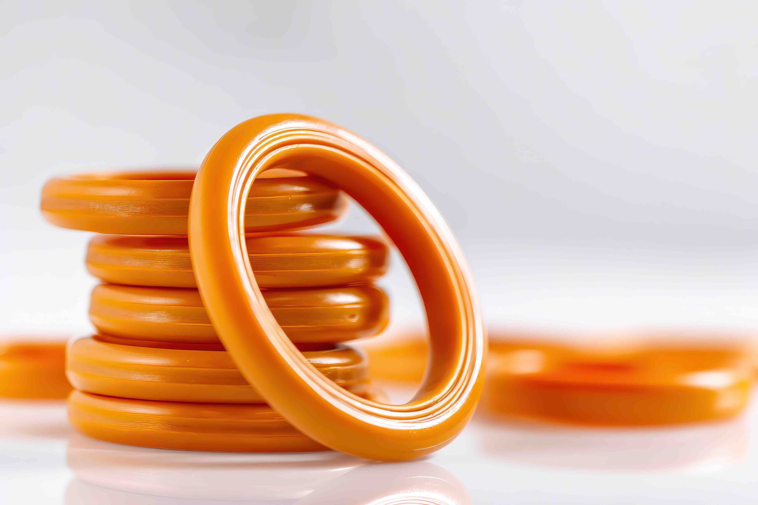 Collection of orange silicone rubber O ring seals on a white backdrop.
